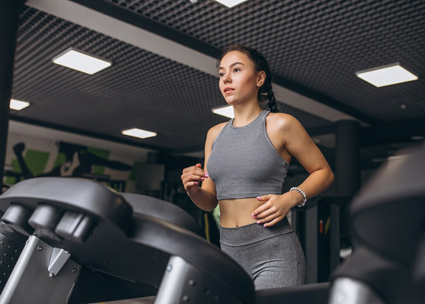 Молодая девушка занимается на беговой дорожке в современном спортивном зале